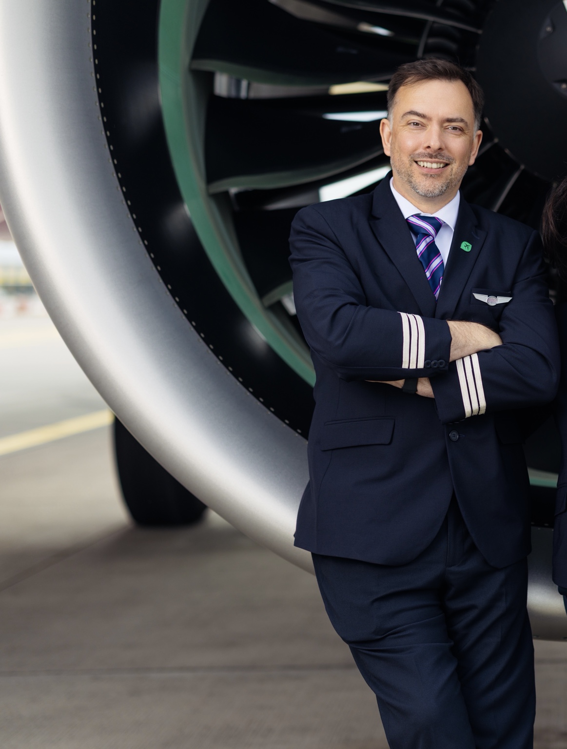 Tom Copestake standing beside an aircraft engine in pilot uniform